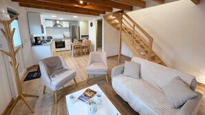 A modern living room with a sofa, two armchairs, a coffee table, and a staircase leading to an upper level. - New - small cosy cottage for 4 near the sea (Landunvez)