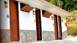 Un edificio con varias puertas y ventanas de madera, base de piedra y pared superior blanca.