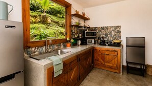 Una cocina con pileta integrada, muebles de madera, microondas, estufa y refrigerador.