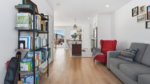 Ein modernes Wohnzimmer mit einem grauen Sofa, einem roten Sessel und einer Bücherwand voller Bücher.