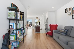 Ein modernes Wohnzimmer mit einem grauen Sofa, einem roten Sessel und einer Bücherwand voller Bücher.