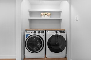 A laundry room with two front-loading washing machines and a shelf above them. - Private 4BR/3BA  Home Near IAH• Sleeps 9•Fast WIFI•Work Stays & Groups (Houston)