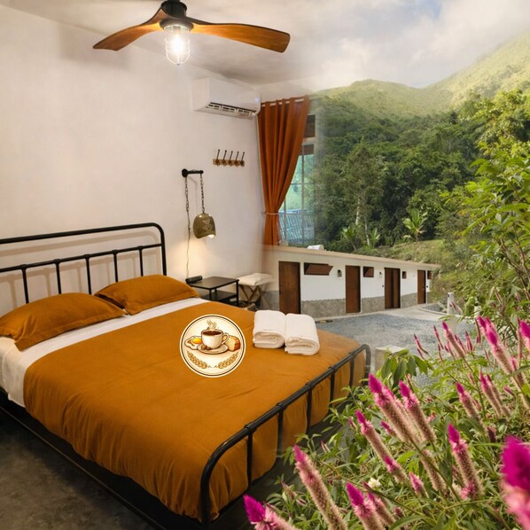 Ein Schlafzimmer mit Bett, Deckenventilator, Klimaanlage, kleinem Tisch, Stuhl und Blick auf eine Berglandschaft.