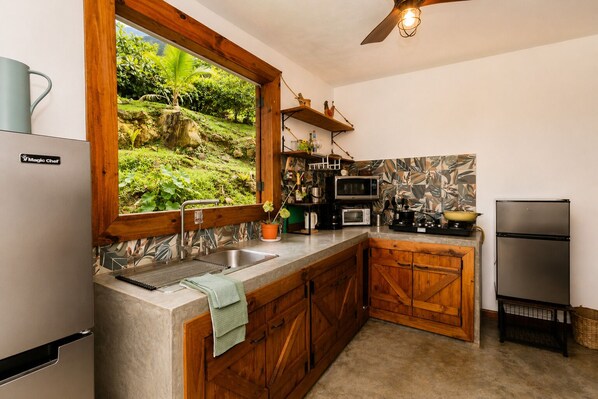 Una cocina con pileta integrada, muebles de madera, microondas, estufa y refrigerador.