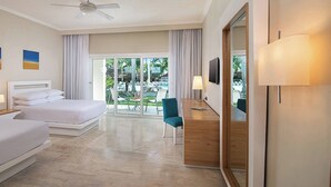 A hotel room with two beds, a desk, a chair, a TV, and a view of the outdoors. - Room-modern Beach Studio Next to the bea (Puerto Plata)