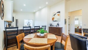 Un comedor con una mesa redonda, sillas negras y una planta en maceta.