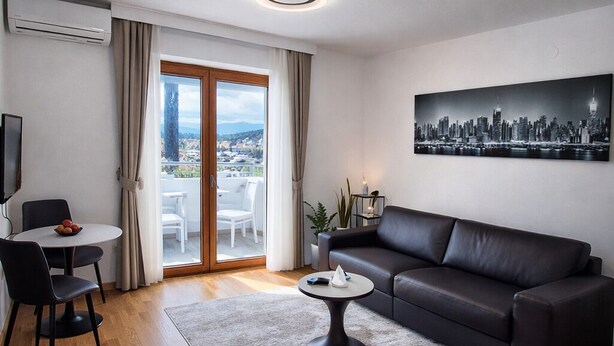 Ein modernes Wohnzimmer mit einer schwarzen Ledersofa, einem runden Couchtisch und einem Stadtbild an der Wand.