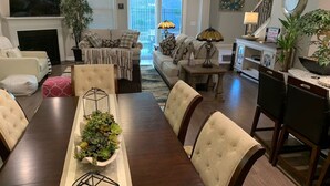 Un comedor con una larga mesa de madera, sillas acolchadas y un centro de mesa con plantas verdes.
