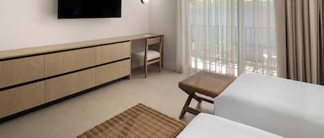 A hotel room with a bed, a desk, a television, and a large window with curtains.