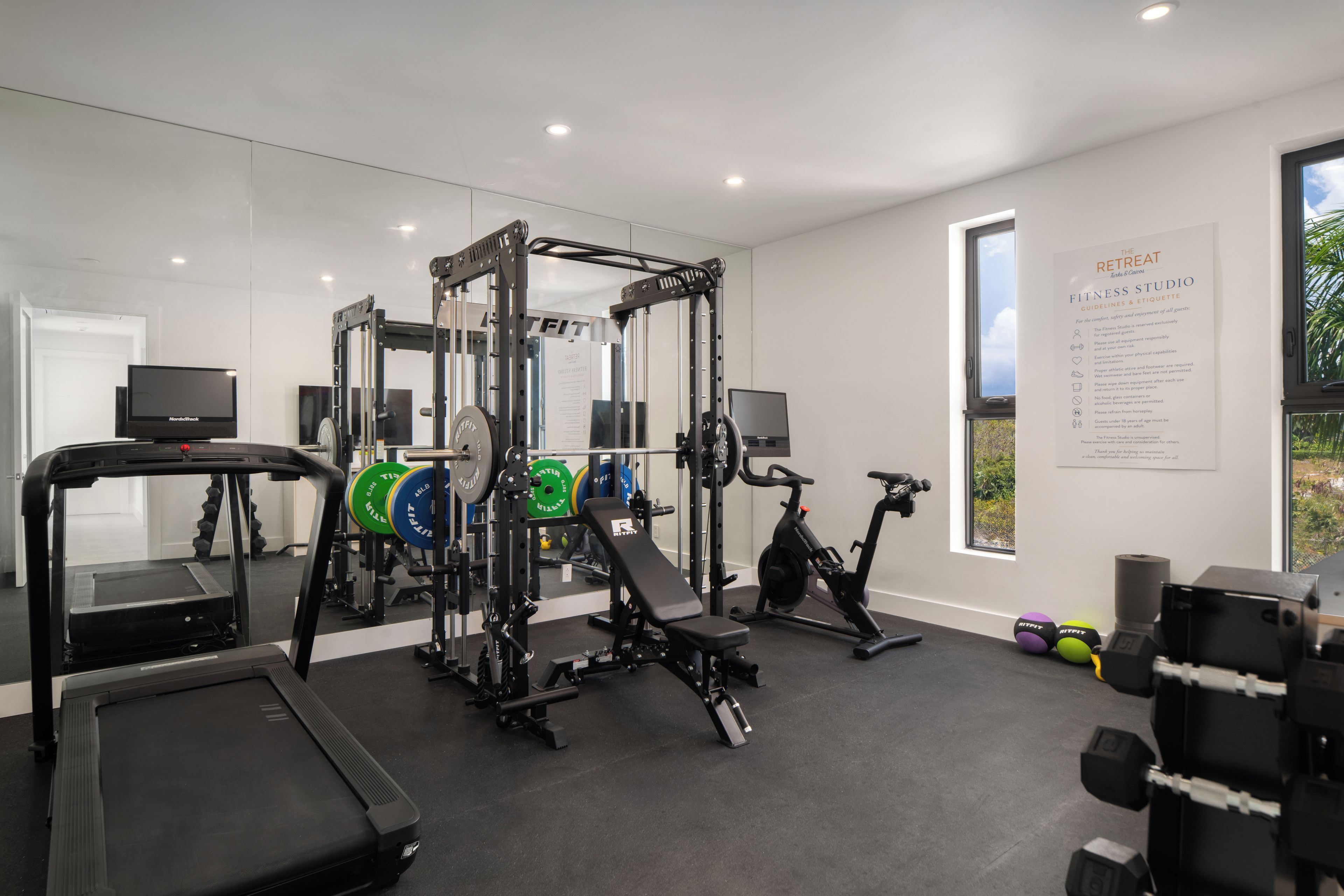 Un gimnasio moderno con equipo cardiovascular, estaciones de levantamiento de pesas y una cinta de correr.