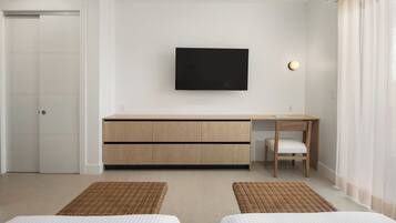 Una habitación de hotel moderna con una cama, un escritorio, una silla, un televisor y una puerta.