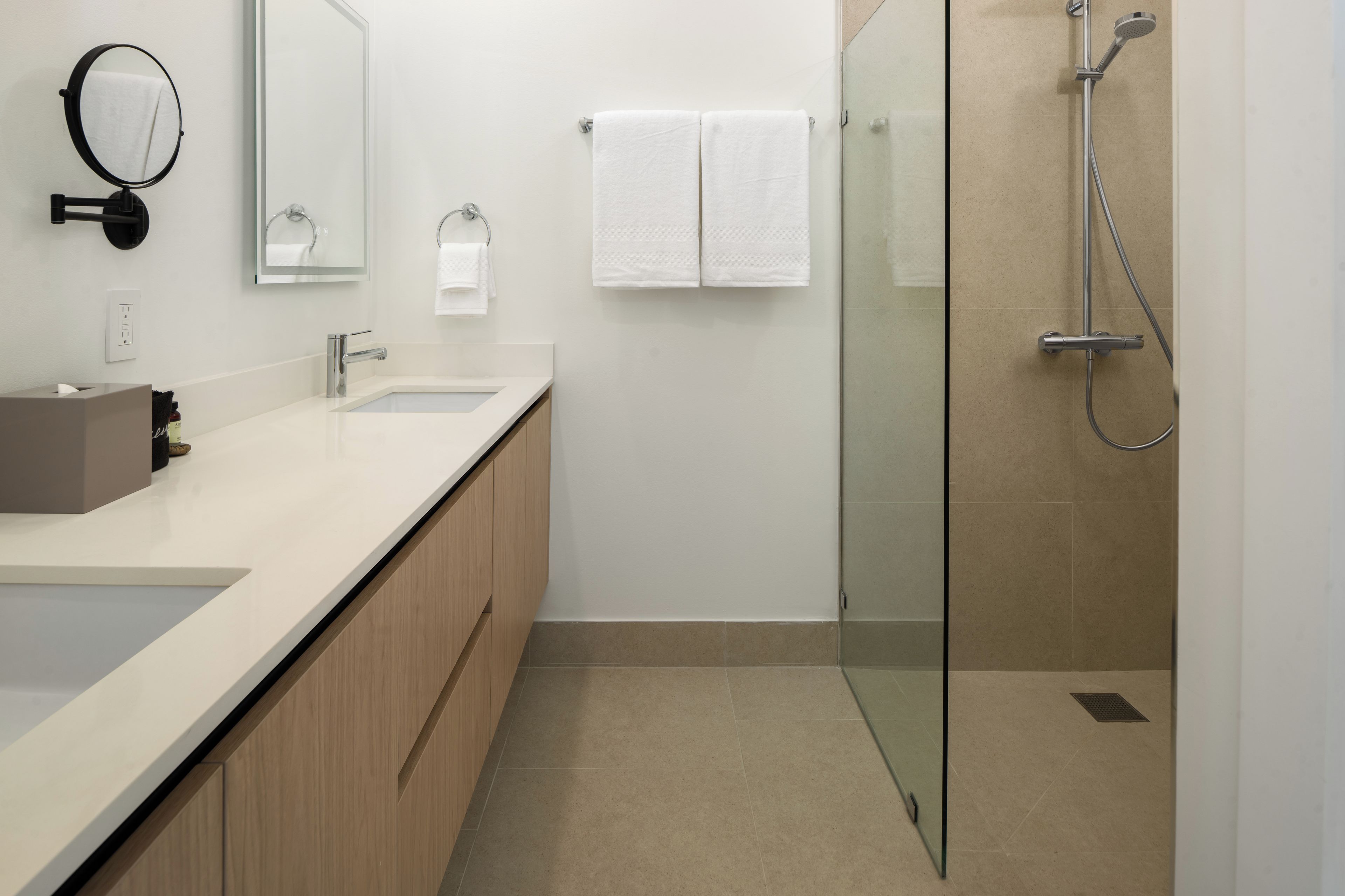 Un bagno moderno con cabina doccia in vetro, lavabo con specchio e porta asciugamani.