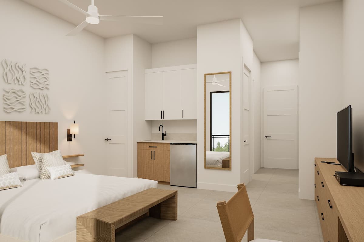 Een moderne slaapkamer met een groot bed, een houten bankje, een televisie en een keukenhoek met kastjes en een spoelbak.