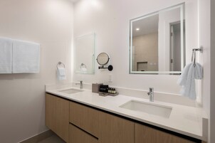 Un baño moderno con dos lavamanos, un espejo grande y un mueble de tocador con un armario de madera.
