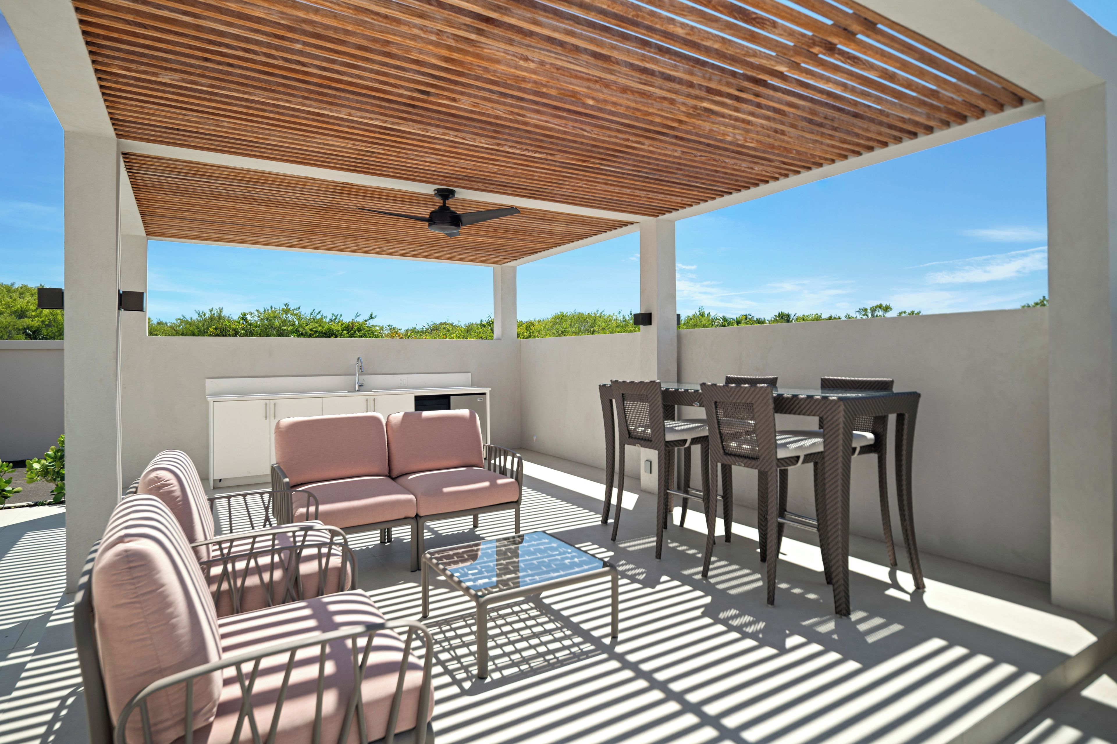 Un patio al aire libre con ventilador de techo, sofá, mesa y sillas.