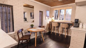 Een gezellig eetgedeelte met een bakstenen muur, houten plafond en een ronde tafel met stoelen.