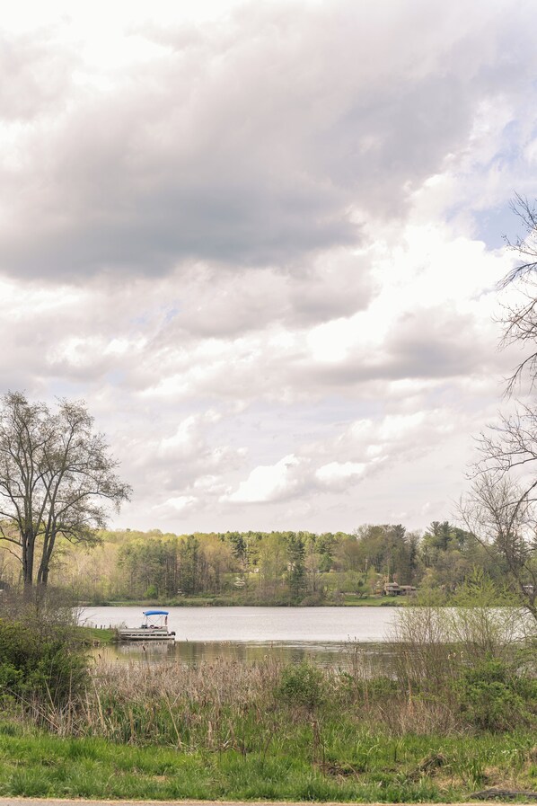 A lake with a boat docked on the shore, surrounded by trees and vegetation. - The Anchorage - Quiet Stay near Lake Logan (Logan)
