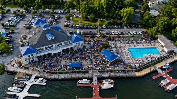 An aerial view of a waterfront property with a large building, a swimming pool, and docked boats. - Lighthouse Cottage | Ocean Pines, Golf & OC Beach (Ocean Pines)