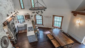 A kitchen with a central island, a dining area with a wooden table, and a sign that reads "FARMHOUSE". - Peaceful Pond Cottage (Ravenna)