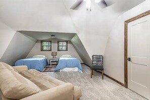 Une chambre avec deux lits, un canapé, une chaise et une porte.