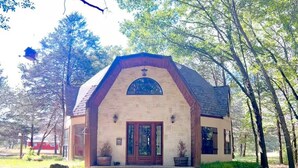 A single-story building with a pitched roof, a central entrance with double doors, and a small porch area. - Peaceful Pond Cottage (Ravenna)
