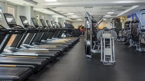 Ett gym med flera löpband uppradade i rader, styrketräningsmaskiner och en vägg täckt med speglar.