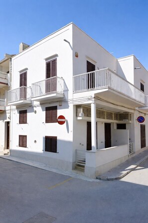 Un edificio blanco con balcones, una señal de prohibido entrar y un letrero azul de prohibición.