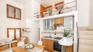 A compact kitchen with a dining area, a staircase, and a balcony with decorative pillows. - VERY NICE RENOVATED APARTMENT JUST 20 METERS FROM THE BEACH! (Donnalucata)