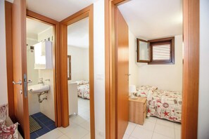 Un dormitorio con cama, mesita de noche y ventana con persianas.