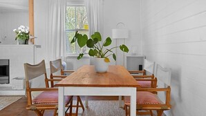Uma sala de jantar com uma mesa e cadeiras de madeira, um vaso de planta e uma cabeça de veado montada na parede.