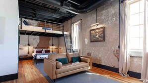 A loft-style room with a bunk bed, a sofa, and a ladder.