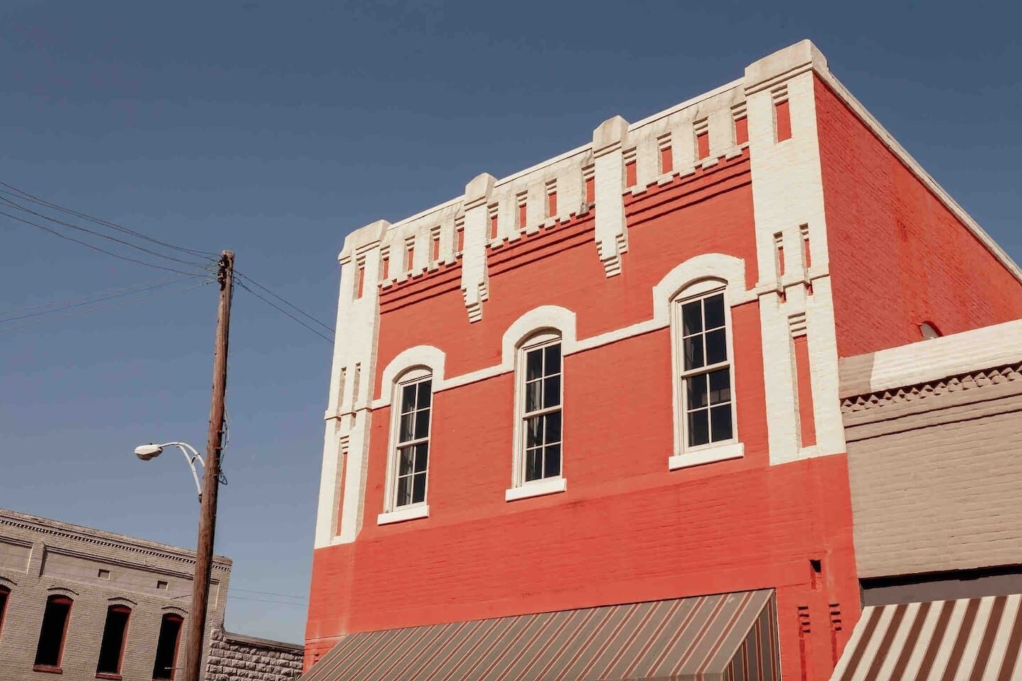 Un edificio rojo con detalles blancos, una farola y un poste de luz.