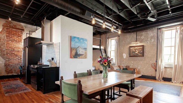 A dining area with a wooden table, green upholstered chairs, and a bench.