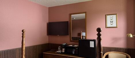 A hotel room with a bed, a dresser, a television, a mirror, and a chair.