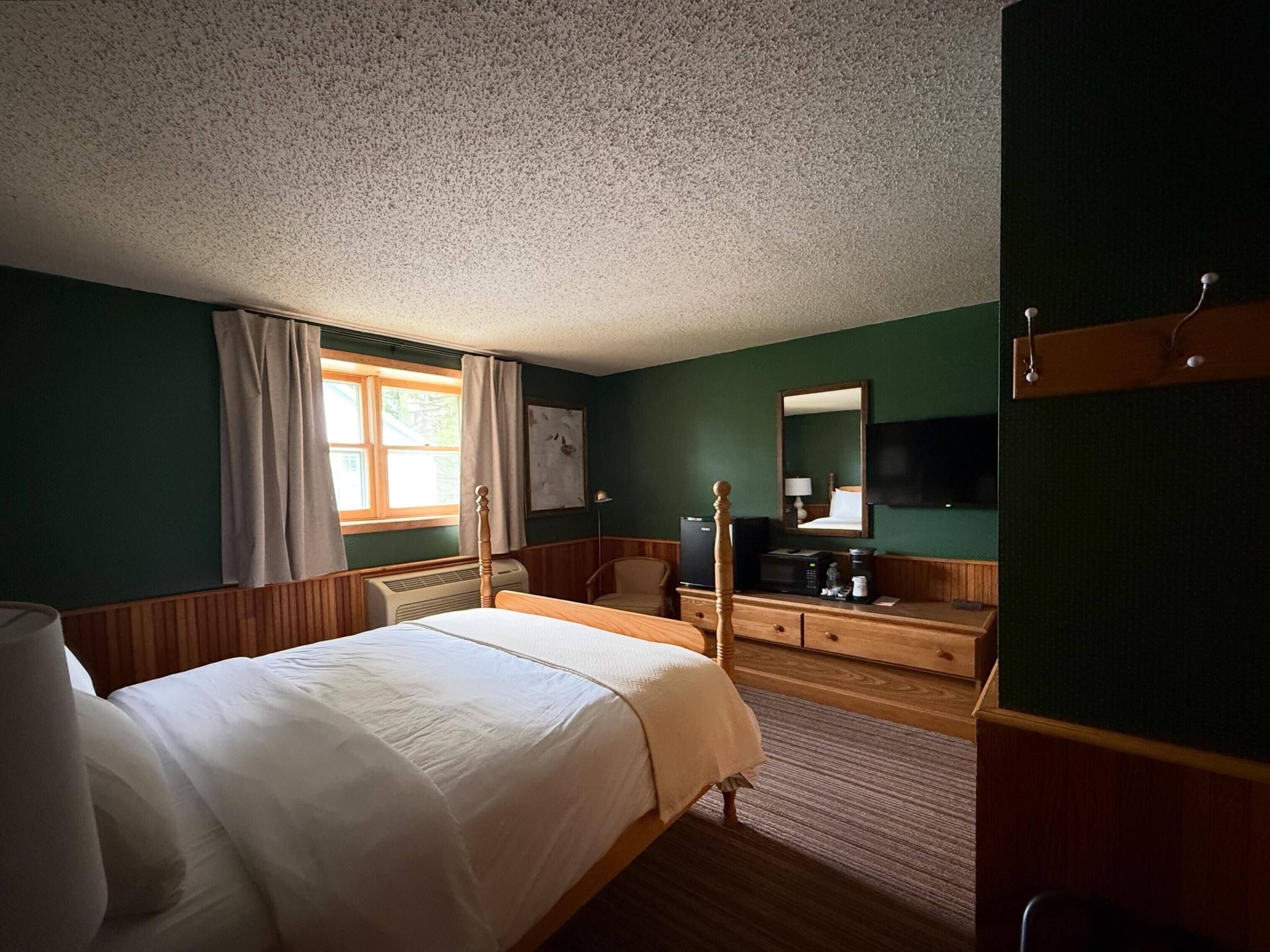 Een slaapkamer met een bed, een kaptafel, een spiegel en een televisie.