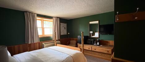 Een slaapkamer met een bed, een kaptafel, een spiegel en een televisie.