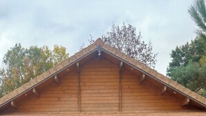Ein Holzgebäude mit einem kiermusikplatten befestigten Eingangsbereich und einer Bank davor.