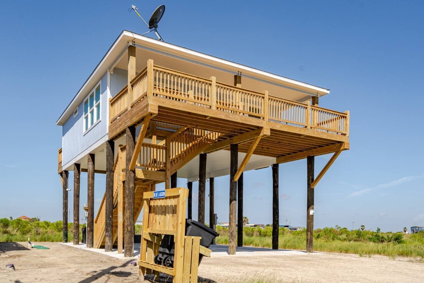 A wooden elevated house with a balcony, a satellite dish, and a sign reading "BLUE LAGOON".