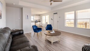 Un salon moderne avec un canapé en cuir, une table basse ronde et deux fauteuils bleus.
