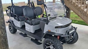 Une voiturette de golf dotée d’un pare-brise transparent, de deux sièges et d’un système de suspension surélevé.
