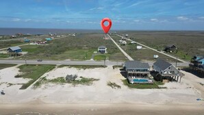 Vue aérienne d’une zone côtière avec une plage, des maisons et une route.
