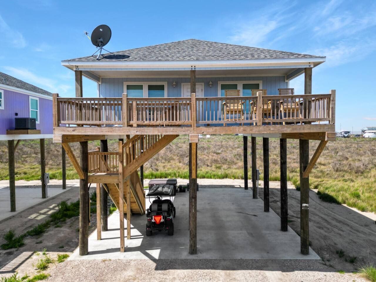 A house with a deck, a satellite dish, and a vehicle in the driveway.