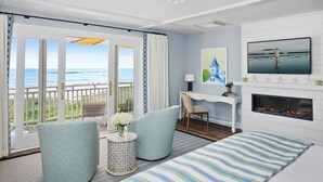 Een kamer met balkon, open haard, bureau en televisie.