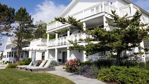 A large, white, two-story house with a balcony and a covered porch.