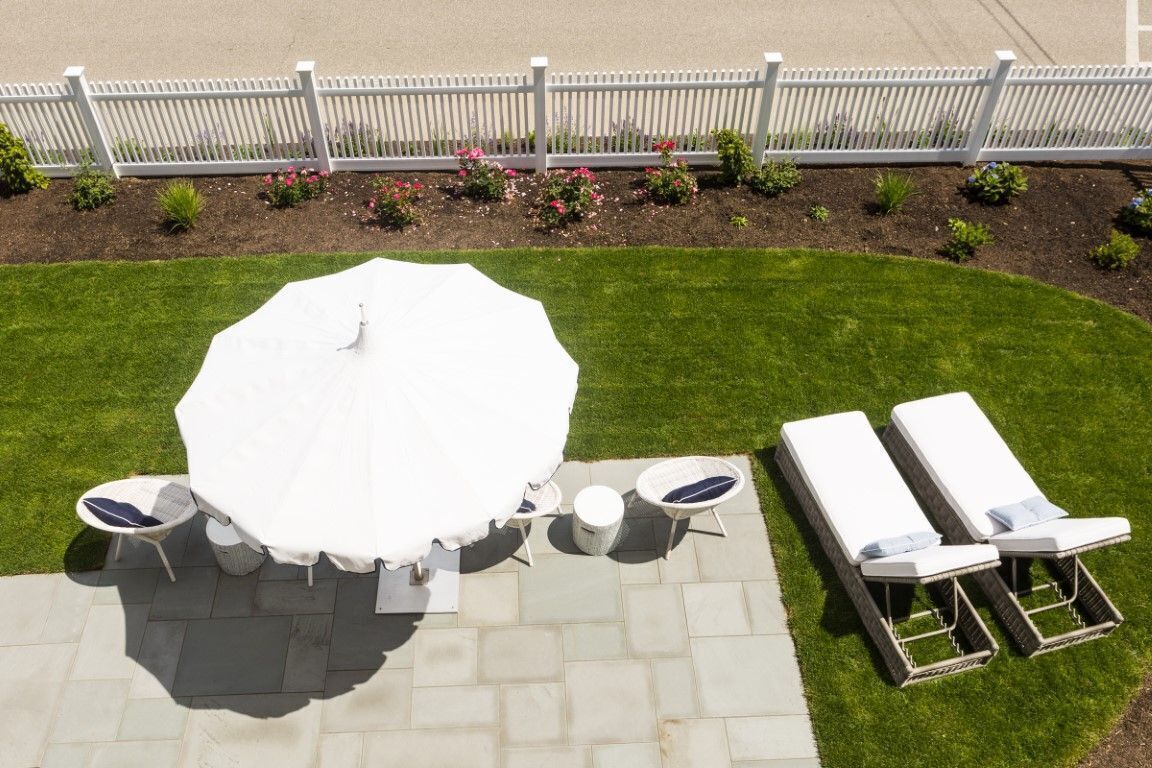 Eine Terrasse mit einem runden Tisch, vier Stühlen, einem kleinen runden Beistelltisch und zwei Liegestühlen.
