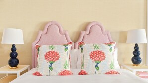 A neatly made bed with two decorative pillows featuring floral patterns, flanked by two bedside tables with lamps.