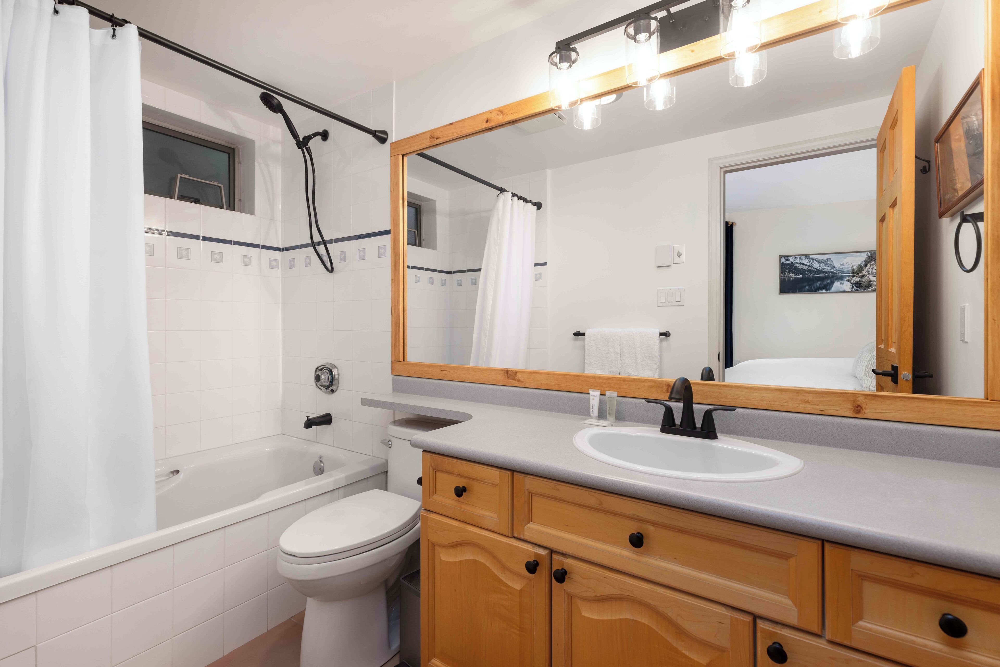 A modern bathroom with a bathtub, toilet, sink, and wooden vanity.