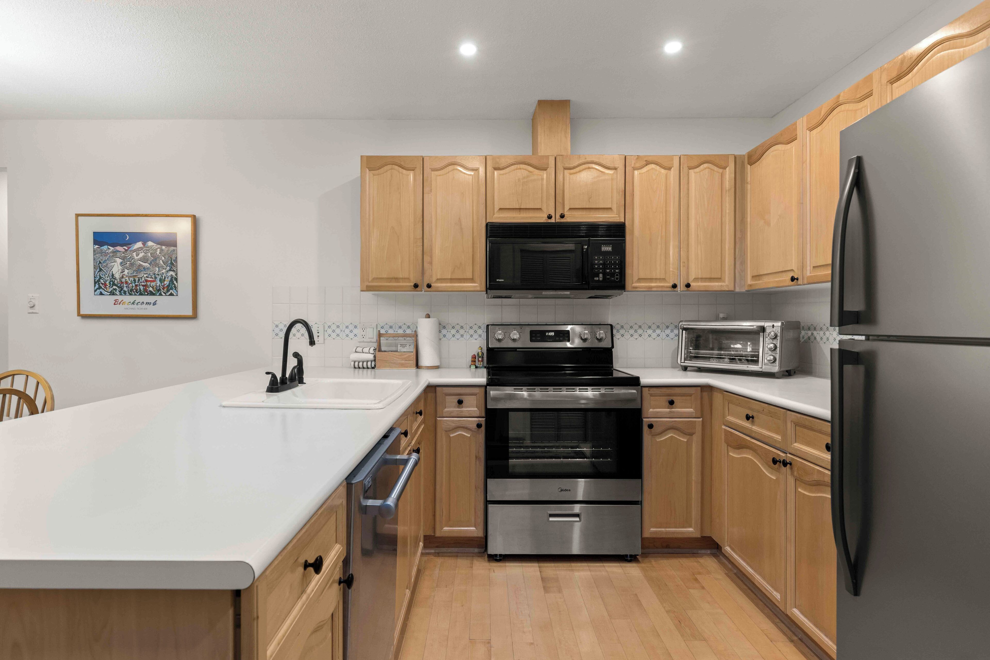 A modern kitchen with wooden cabinets, stainless steel appliances, and a white countertop.