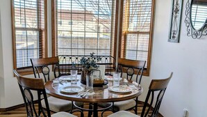 A dining area with a round table, six chairs, and a hanging light fixture.