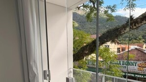 A balcony with a glass door, a view of a restaurant, and a mountainous landscape.